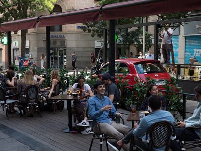 Unos operarios instalan un toldo en una terraza puesta en plazas de aparcamiento en la calle Ponzano de Madrid.