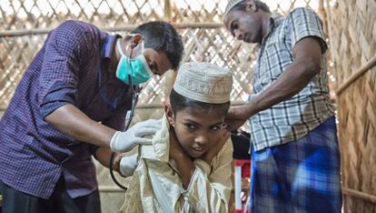 Un médico de MSF inspecciona la espalda de un niño con varicela en presencia de su padre.
