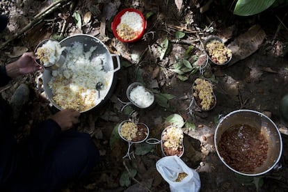 Un soldado se sirve una porción de arroz, huevos, salchichas y frijoles, para el desayuno, en un campo oculto en el estado de Antioquia.