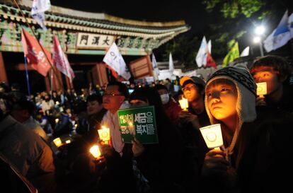 Indignados portan velas y carteles de protesta en la marcha que ha recorrido Seúl.