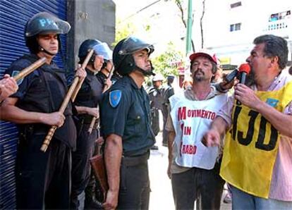 Un piquete se concentra ante la puerta de un comercio vigilado por varios policías.