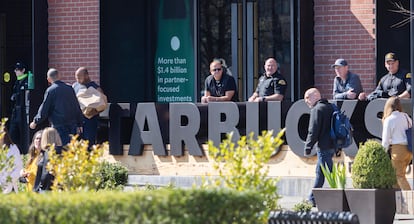 Private security watches a protest outside Starbucks Corporate Headquarters, Wednesday, March 22, 2023, in Seattle. Starbucks workers and labor activists rallied outside the company’s Seattle headquarters Wednesday to protest what they describe as union-busting efforts by executives. (Ken Lambert/The Seattle Times via AP)