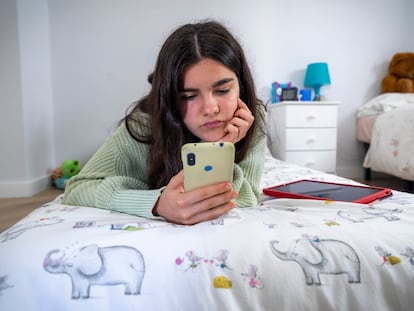 Una adolescente durante el confinamiento trastea con el móvil en su habitación.