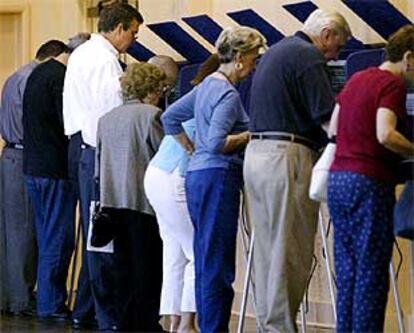 El gobernador de Florida, Jeb Bush (izquierda, con gafas), vota utilizando un nuevo sistema de terminales, ayer en Coral Gables.