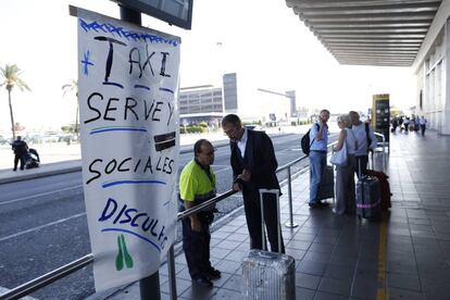 Varios viajeros del aeropuerto del Prat (Barcelona) esperan la llegada de un taxi durante la jornada de huelga.