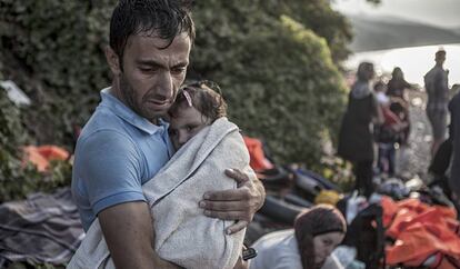 Un hombre abraza y seca a su hijo momentos después de desembarcar en la costa norte de la isla Lesbos tras cruzar el Mar Egeo en un una barca de plástico.