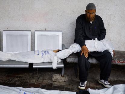 Un hombre sentado junto a los cadáveres de dos niños en el hospital de Rafah, el pasado 6 de mayo.