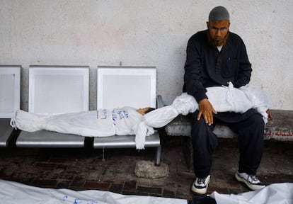 Un hombre sentado junto a los cadáveres de dos niños en el hospital de Rafah, el pasado 6 de mayo.