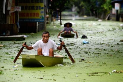 Vecinos se trasladan en barca por las calles inundadas del distrito suburbano de Chuong My, en Hanoi (Vietnam), tras unas fuertes lluvias.