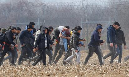 Varios migrantes llevan a un hombre herido cerca del paso fronterizo de Pazarkule en Turquía.