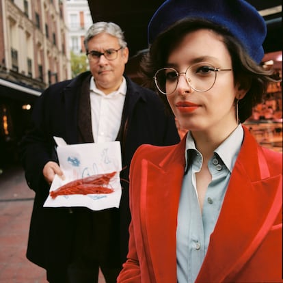 Elizabeth Duval lleva traje de chaqueta de terciopelo rojo, camisa azul, escarpines negros y bolso Diana de piel marrón y asas de bambú, todo de Gucci. Juan Manuel de Prada lleva su propia ropa.