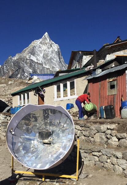 This April 9, 2016 photo shows a solar power water heater in the foreground and a Nepali woman in the background, pouring water into a large kettle in the village of Dughla, Nepal. A trek to Everest Base Camp along mountain paths hugging it's deep gorges offers renewal and a test of mental and physical limits. A trek to Everest Base Camp along mountain paths that hug deep gorges offers renewal and a test of mental and physical limits. Along the way there are sore knees and altitude sickness, but the spectacular landscapes, friendly villagers and moments of tranquility make the journey an unforgettable experience. (AP Photo/Karin Laub)