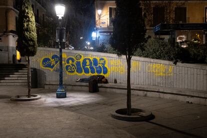 Una persona duerme de madrugada en la Plaza del Dos de Mayo, en Malasaña.