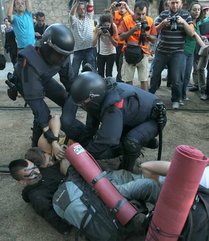 Dos Mossos d'Esquadra intentan apartar a varios jóvenes durante la concentración de más de 2.000 indignados frente al Parlamento catalán.