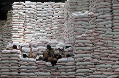 Un grupo de trabajadores descansa sobre unos sacos de arroz en el interior de un edificio de la Autoridad Nacional de Alimentos en Taguig (Filipinas).