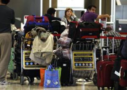 Numerosos pasajeros esperan en los mostradores de Iberia en el aeropuerto de Barajas. EFE/Archivo