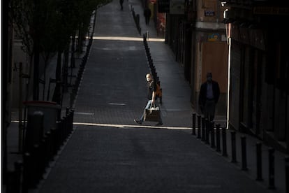 Un hombre protegido con una máscara y cargado con varias bolsas de comida, en una calle de Madrid, este sábado.