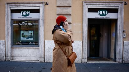 Una mujer habla por un teléfono móvil mientras pasa por una sucursal de BPM en Roma el 17 de diciembre.