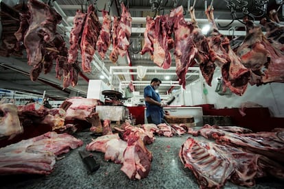 Un carnicero, protegido con mascarilla, se dispone a cortar una pieza de carne en un mercado de Manama (Bahréin).