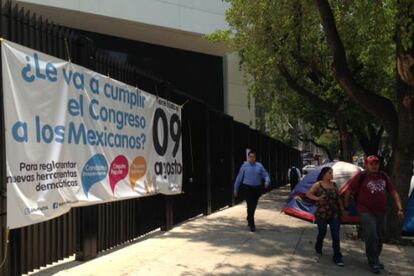 Residents walk by a poster in favor of political reform hung outside the Senate in Mexico City in August.