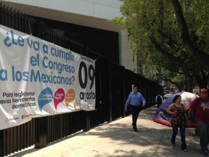 Residents walk by a poster in favor of political reform hung outside the Senate in Mexico City in August.