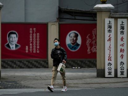 Un hombre con una máscara camina frente a los retratos del presidente chino Xi Jinping y el difunto presidente Mao Zedong, el pasado 10 de febrero en Shanghái.