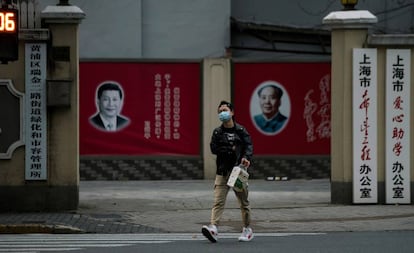 Un hombre con una máscara camina frente a los retratos del presidente chino Xi Jinping y el difunto presidente Mao Zedong, el pasado 10 de febrero en Shanghái.