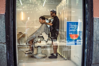 Un cartel contra el genocidio en Gaza, colgado en el escaparate de la peluquería 'Dreir Hair Club', en Malasaña, Madrid.