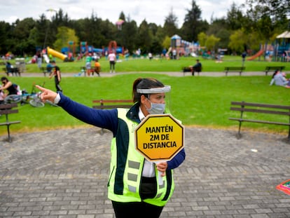 Una vigilante de seguridad con un cartel pidiendo distancia de seguridad, en un parque de Bogotá (Colombia).