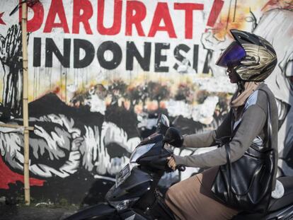 Una motorista delante de uno de los murales de X-Go, en Surabaya.