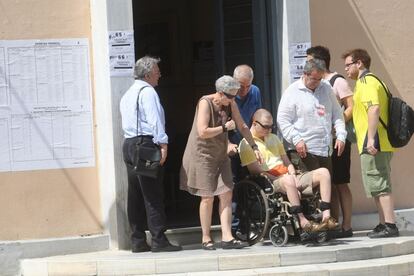 Un grupo de personas ayuda a un hombre en silla de ruedas a entrar a un colegio electoral en Salónica.