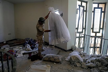 Un soldado iraquí sostiene un vestido de novia encontrado en una casa abandonada, previamente ocupada por militantes del Estado Islámico, en el oeste de Mosul.