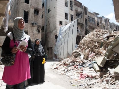 Dos mujeres aguardan la distribución de cajas con comida en el campo de refugiados palestinos de Yarmuk. / Natalia Sancha