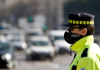 Un policía municipal trabaja con una mascarilla para evitar la contaminación en Madrid.