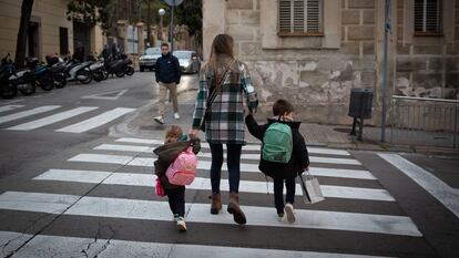 Una mujer acompaña a dos niños al colegio en Cataluña.