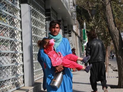 Un hombre abandona con una niña en brazos los alrededores del hospital tras las dos explosiones, este martes en Kabul.