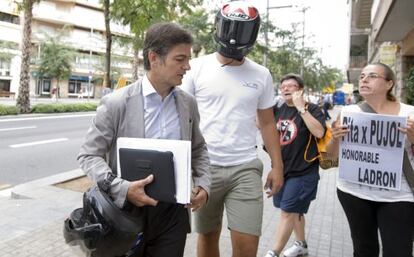 Oriol Pujol, a la izquierda, increpado ayer cundo llegaba, acompañado de un joven con casco de motorista, al domicilio de su padre.