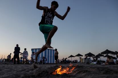 Una persona salta en la playa de la Malvarrosa de Valencia sobre una hoguera.