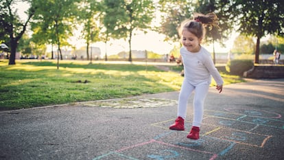 Una niña saltando mientras juega a la rayuela.