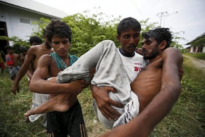 Un refugiado lleva en brazos a su amigo inconsciente tras ser rescatados del mar y puestos a salvo en un campamento, en la región de Aceh.