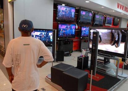 Un hombre mirando pantallas de televisión en Brasil.