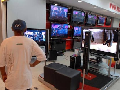 Un hombre mirando pantallas de televisión en Brasil.