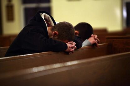 Dos jóvenes en rezan en la iglesia Saint Rose of Lima, cerca de la escuela Sandy Hook.