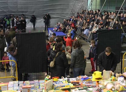 Unos niños recogen regalos en el frontón de Usurbil. Detrás, ex presos de ETA se dirigen a la prensa.