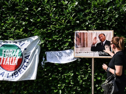 Una mujer toca una imagen de Silvio Berlusconi en un improvisado tributo fuera de su residencia en Arcore, el lunes.