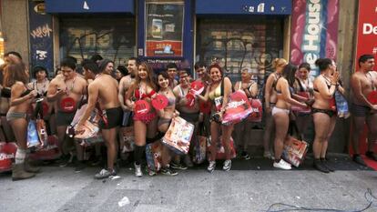 Varias personas esperan a las puertas de un comercio en Madrid, donde arrancan las rebajas con la campaña 'Entra desnudo y sal vestido'.