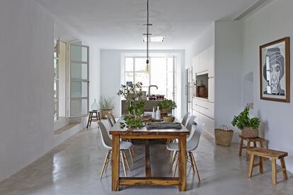 En el centro del comedor se encuentra una gran mesa de madera artesanal acompañada por sillas Eames Plastic Side DSW de Vitra.