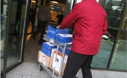 Un hombre transporta un carrito con documentación de una causa judicial y la introduce en los juzgados de Lugo. 