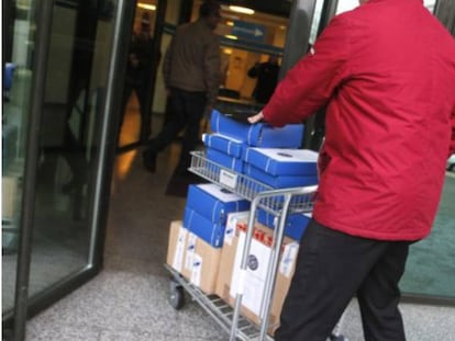 Un hombre transporta un carrito con documentación de una causa judicial y la introduce en los juzgados de Lugo. 