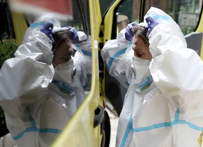 La médica se coloca el traje, con el cristal de la ambulancia como ayuda, momentos antes de entrar en un domicilio, en Madrid.